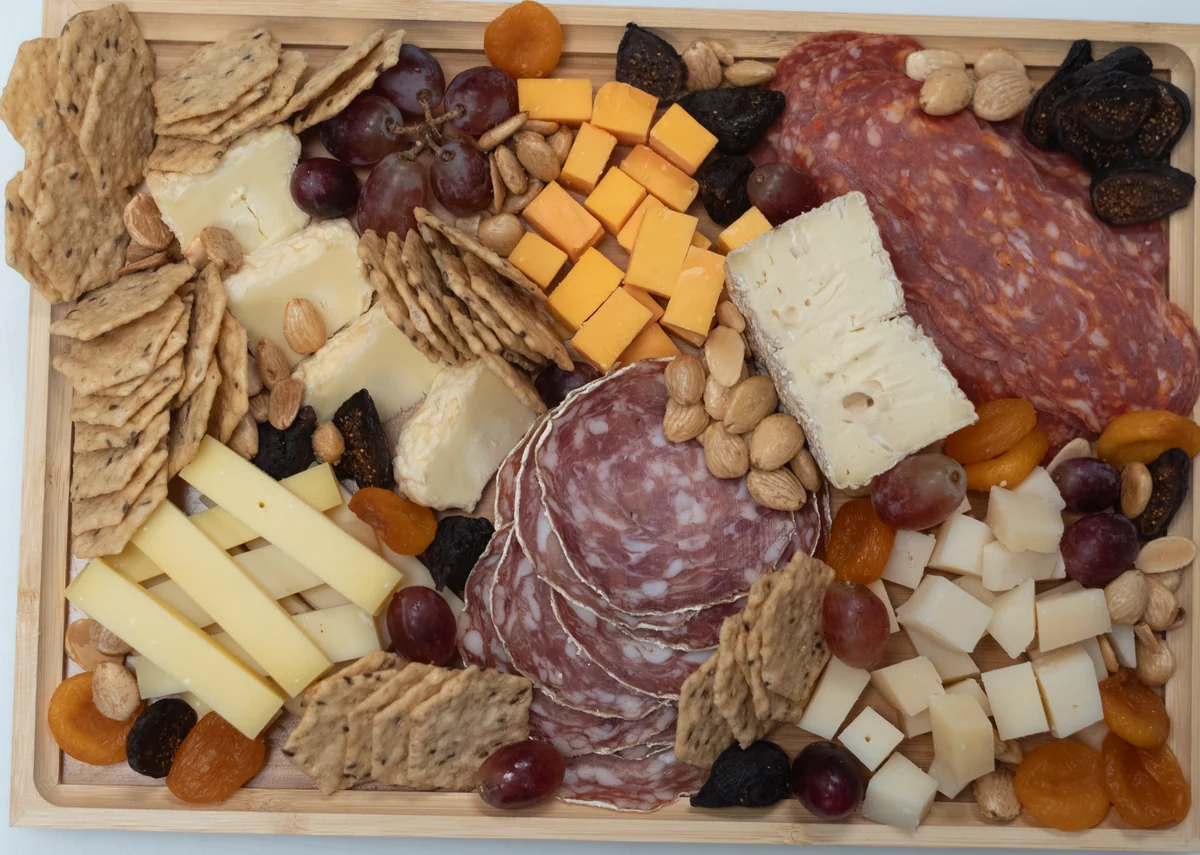 Cheesemonger Collection cheese board with charcuterie, crackers, fruit and nuts